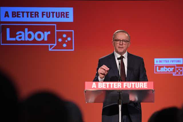Man in suit speaking at lectern bearing words 'A Better Future' against a red background with the word "Labor'