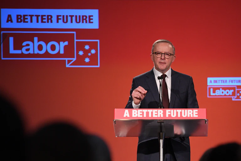 Man in suit speaking at lectern bearing words 'A Better Future' against a red background with the word "Labor'