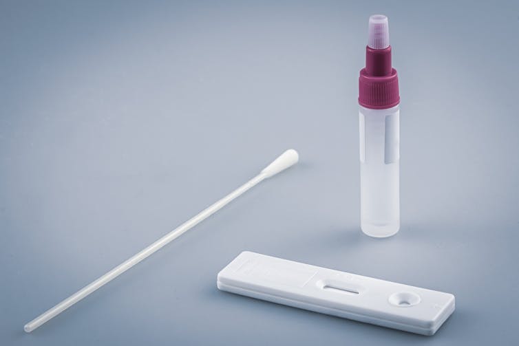 Components of a rapid antigen test: a swab, vial of reagent liquid and a test device.