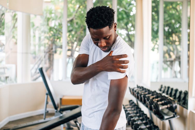 Man in gym holding sore arm