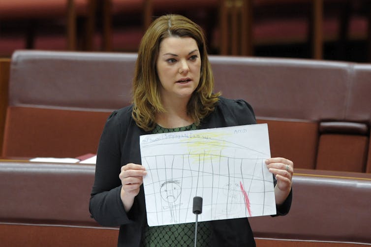 Australian senator holds up drawing by child at Manus.