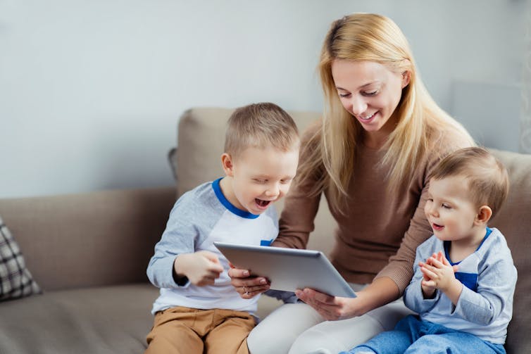 Mum with two small children looking at iPad.