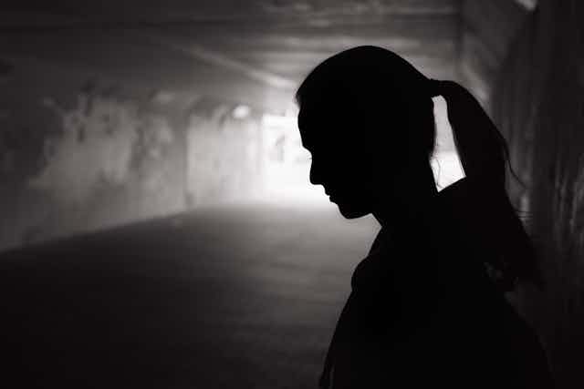 Young woman's profile in a dark underpass.