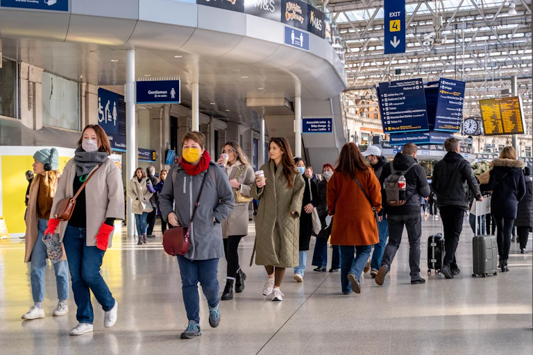 People, some masked and some not, walking through Waterloo station in London