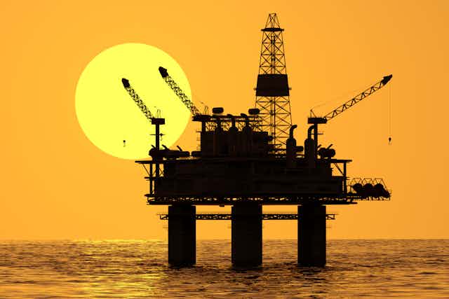 An offshore oil platform in silhouette.