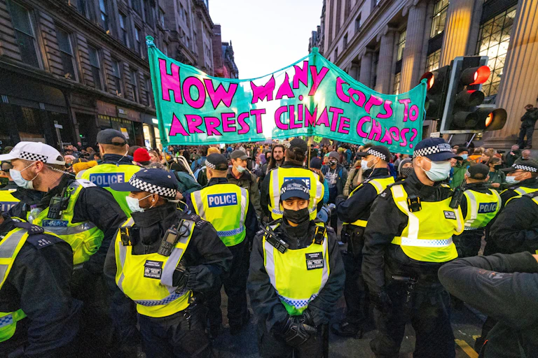 Police form a cordon around a crowd of climate activists.