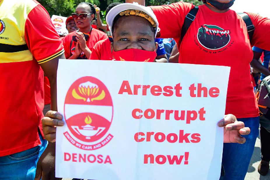 A woman displays a banner while surrounded by other people