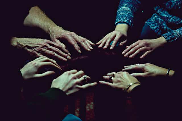 Pairs of outstretched hands form a circle.