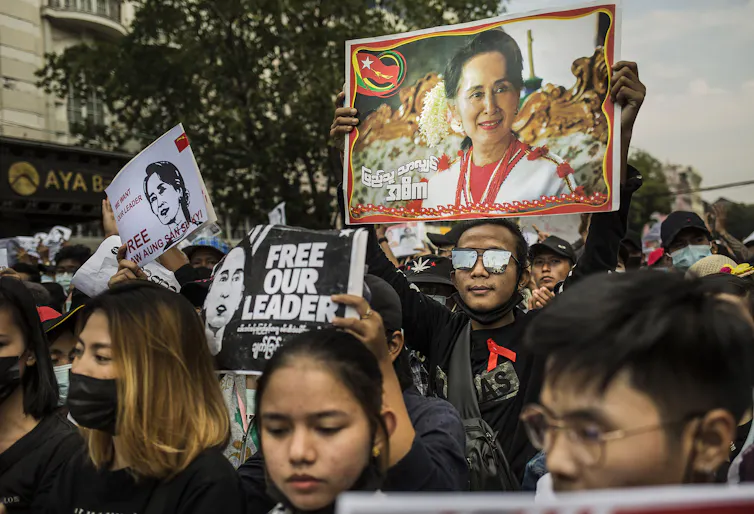 Protesters hold a picture of Aung San Suu Kyi.