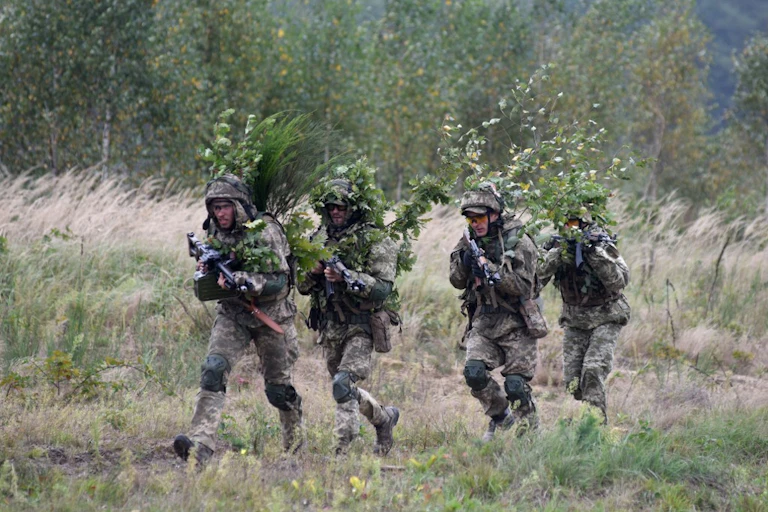 Militaires en tenue de camouflage tenant des fusils mitrailleurs