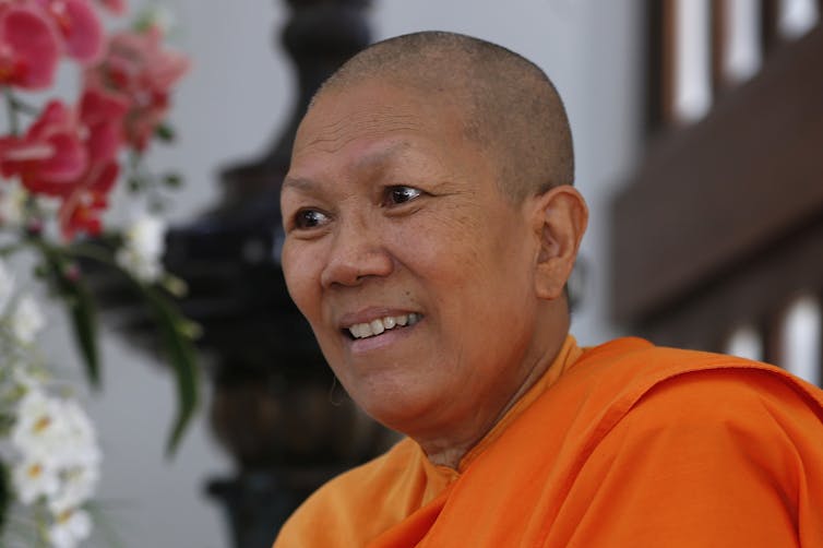 A Buddhist nun, dressed in ochre robes, speaking to an audience.