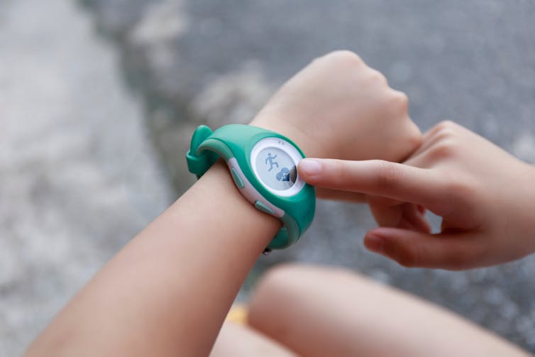 A child touches a green fitness tracker on their wrist