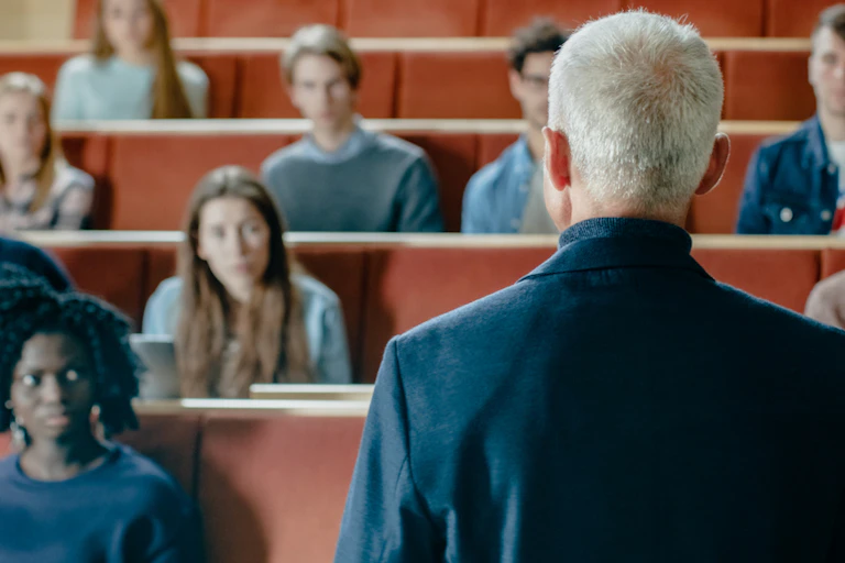 Professeur d'université de dos devant une classe.