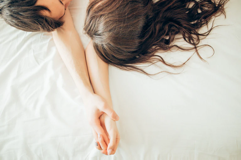 Couple hold hands in bed