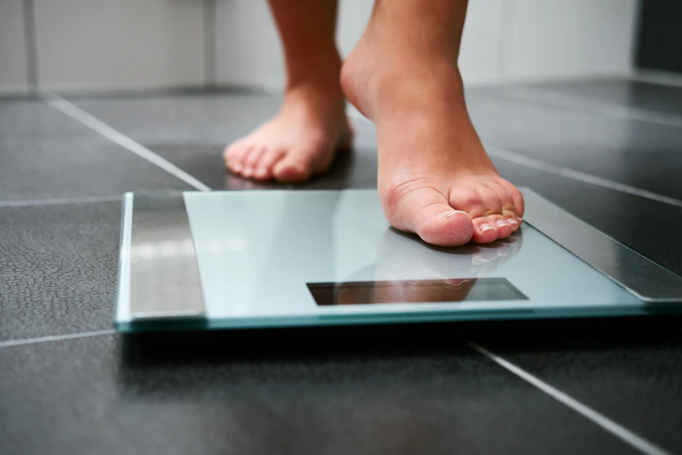 Person steps onto bathroom scales.