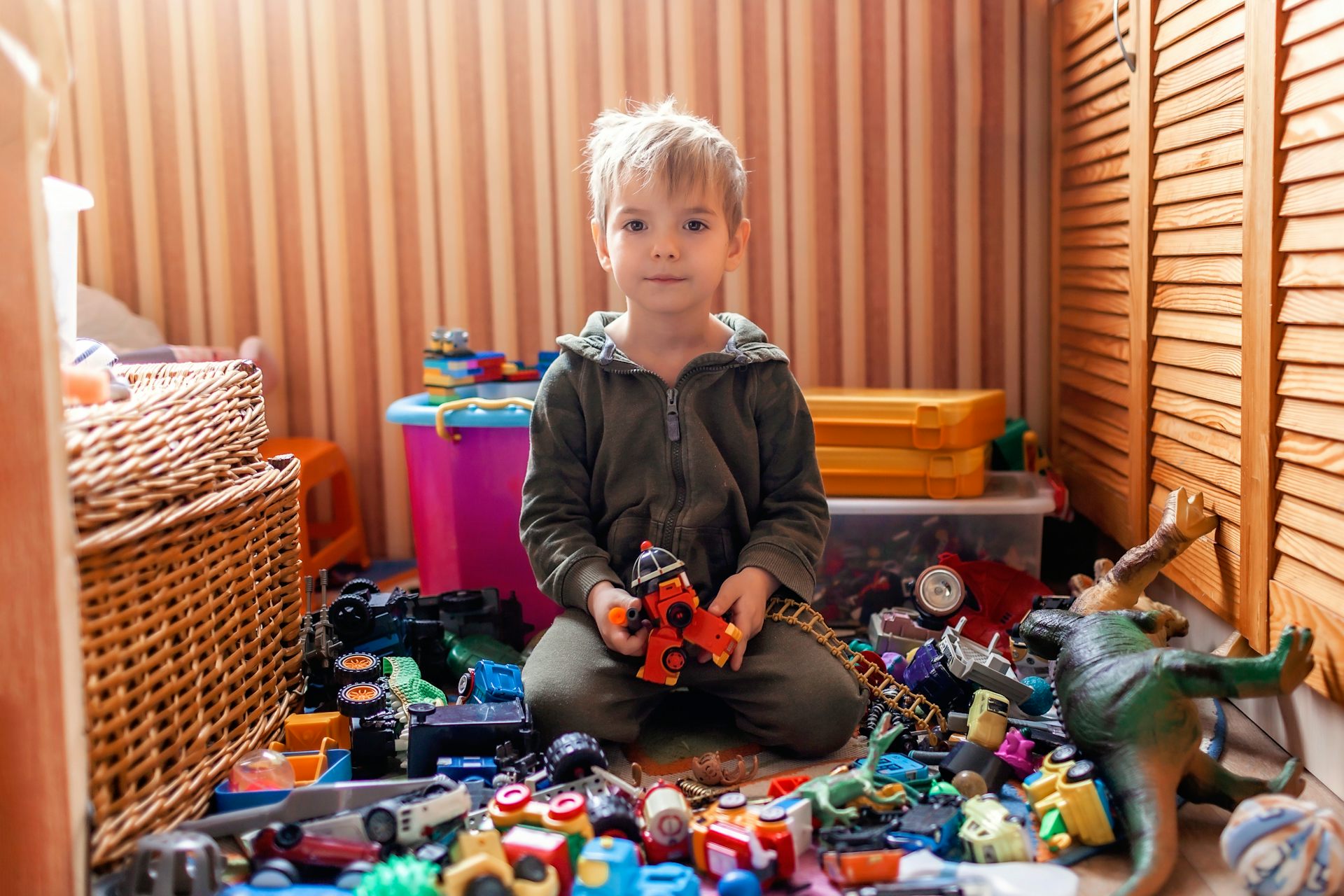 Ребенок убирает игрушки. Много игрушек для мальчиков.