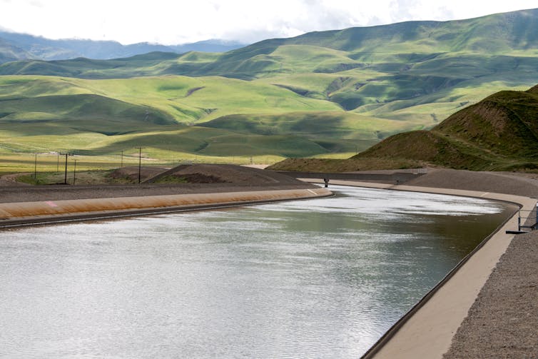 A large, manmade canal flows through low hills.