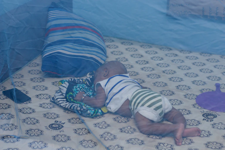 infant sleeping under a bednet