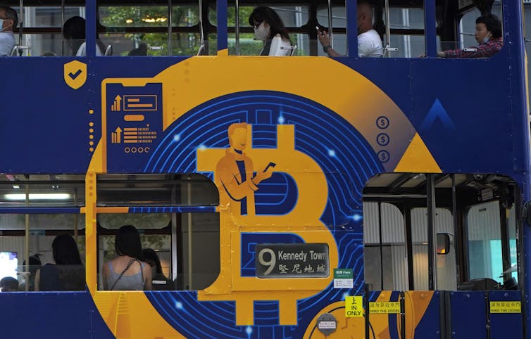 An orange and blue ad for Bitcoin is seen on the side of a tram.