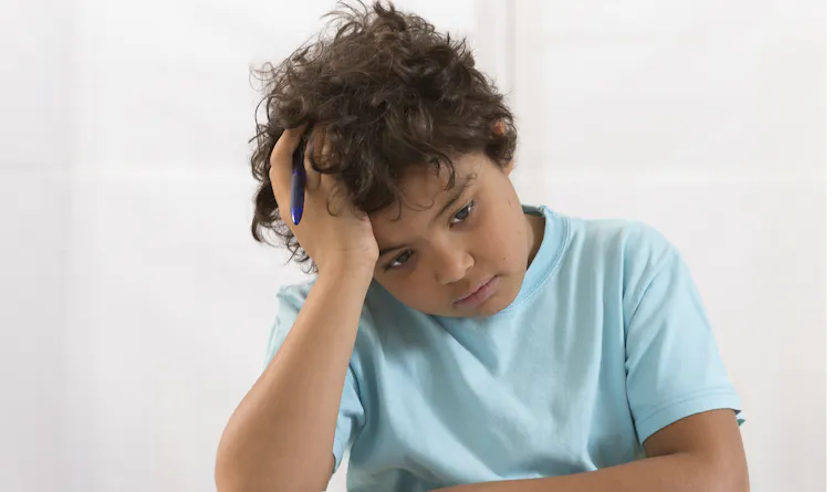 Boy doing homework looking sad