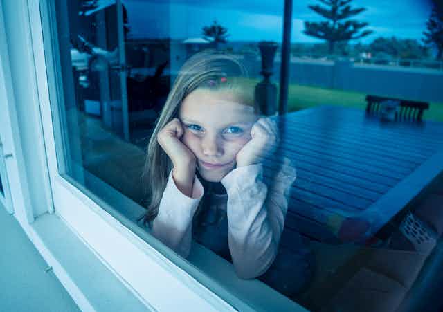 Sad little girl looks out of window