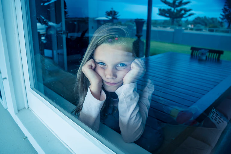Sad little girl looks out of window