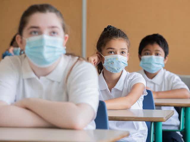 Des enfants portant des masques dans une salle de classe.