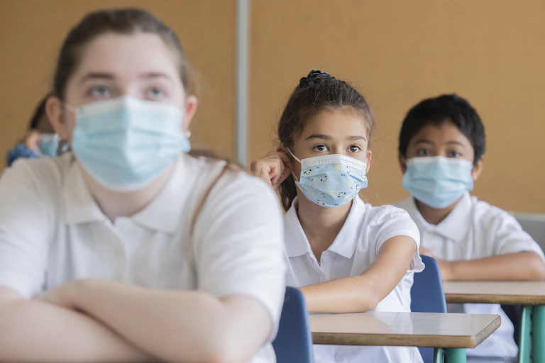 Des enfants portant des masques dans une salle de classe.