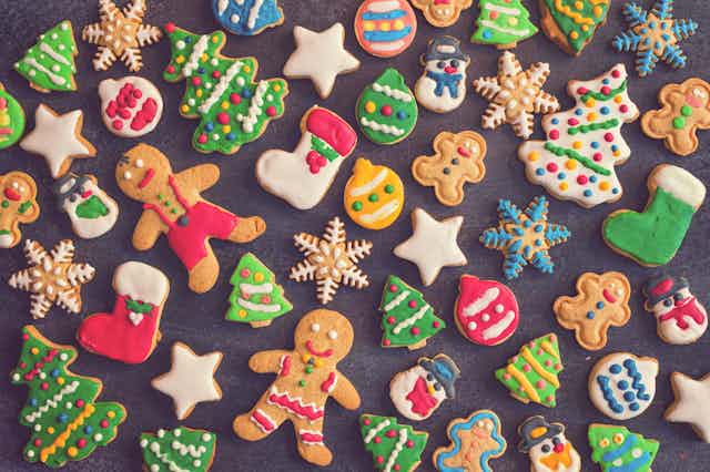 Christmas-themed gingerbread cookies spread out on a grey backdrop.