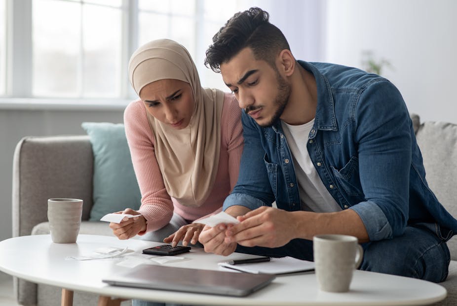 A woman in a head scarf and a man examine documents at a table.