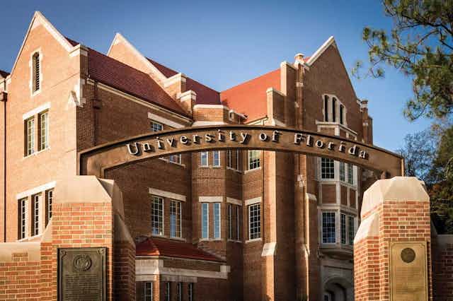 A large brick building behind an archway that says "University of Florida" on it.