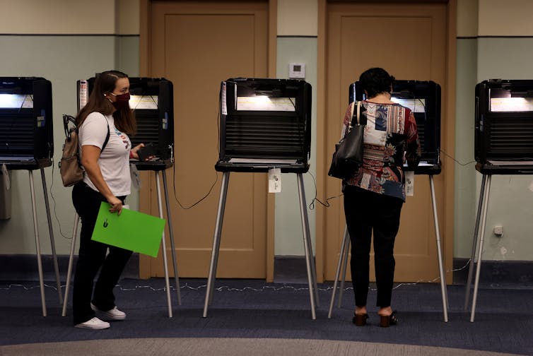 People voting at stand-up voting carrels.