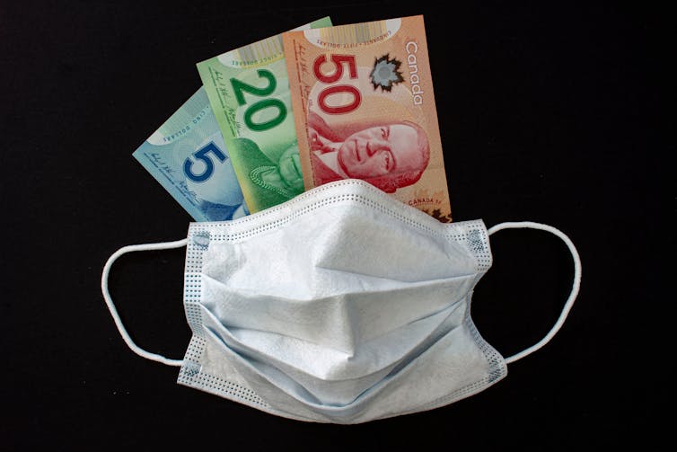A mask covers a 5, 20 and 50 dollar bill