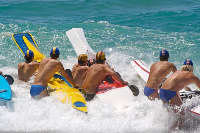 Surf-lifesavers paddle out wearing budgies