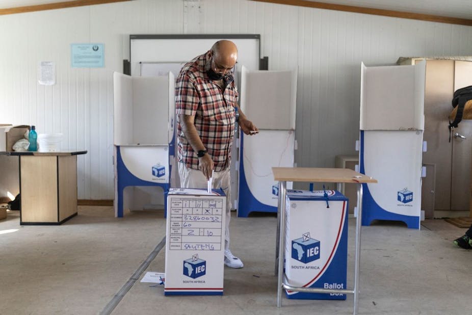 A man dropping his vote into a ballot box.