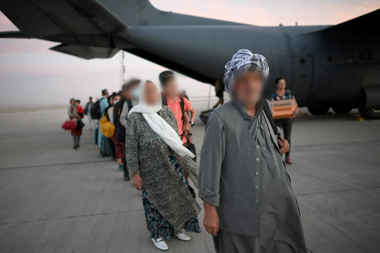 A queue of people with their faces blurred in front of a large military plane