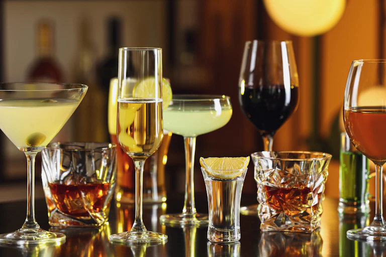 An assortment of different alcohol drinks on a table in a bar.