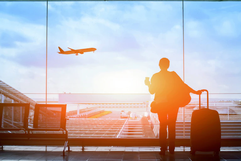 Traveller at airport watching plane take off.