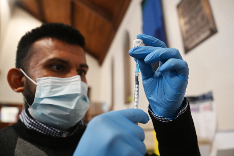 A nurse preparing a COVID booster injection in a church in London.