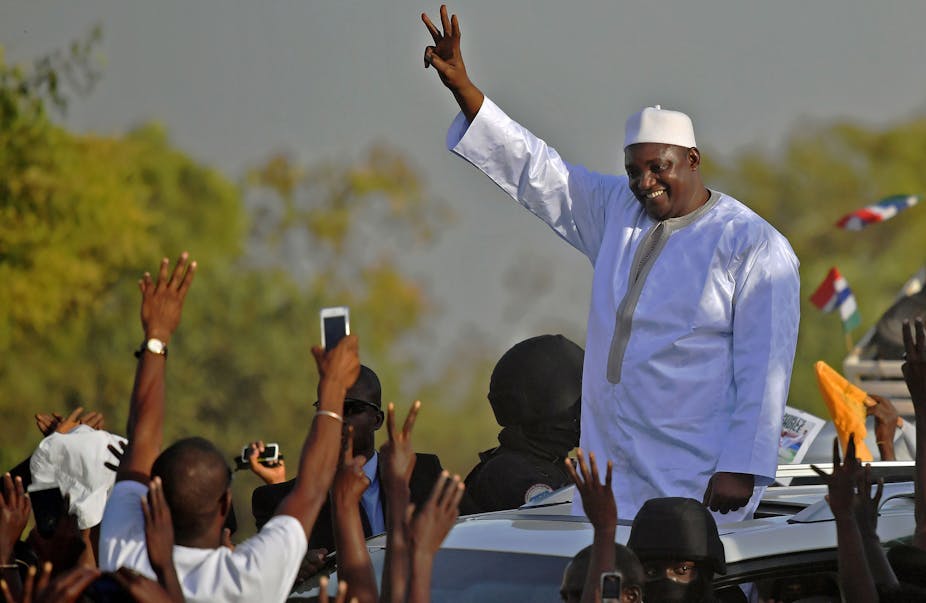 Man dressed in flowing white robes and cap celebrating amidst cheers on the street.