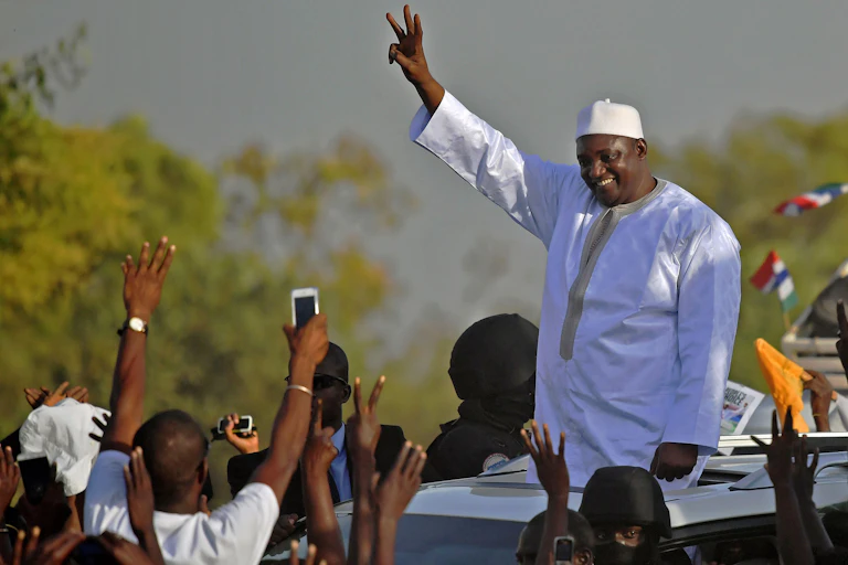 Man dressed in flowing white robes and cap celebrating amidst cheers on the street.