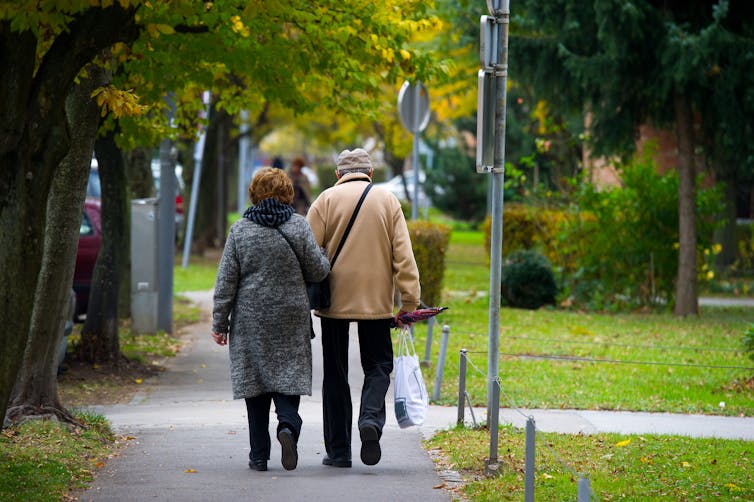 An elderly couple walking down a sidewalk.