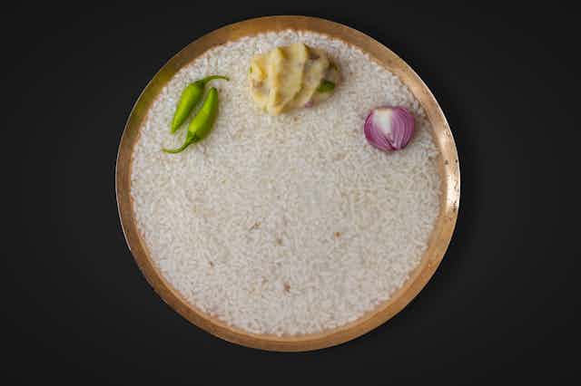 a bowl of rice with a dab of mustard, half a red onion and two green chillies