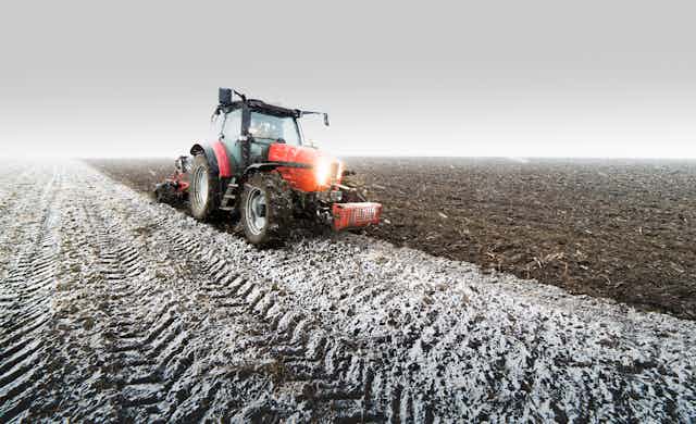  A tractor ploughing a field in winter.
