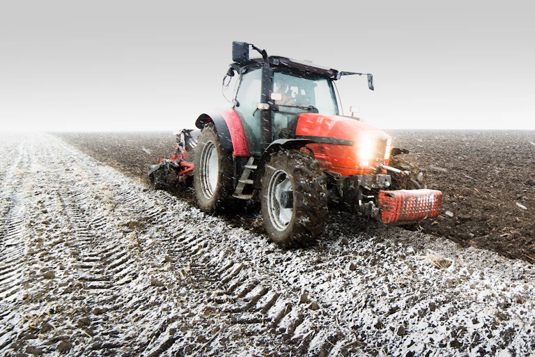 A tractor ploughing a field in winter.