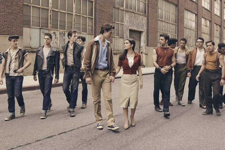 A young couple walks down a city street surrounded by young men.