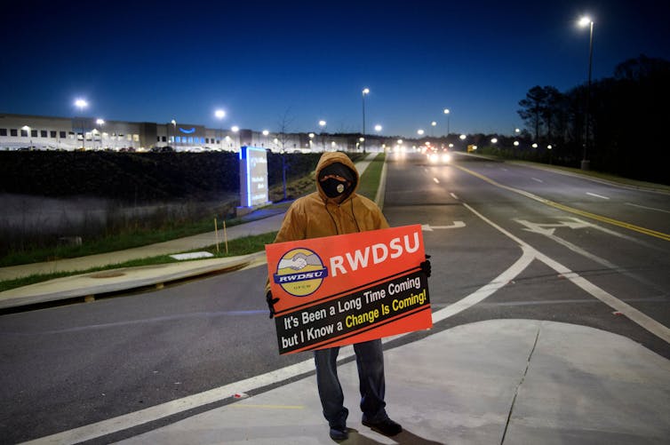 A worker holds a pro-union sign outside an Amazon factory.