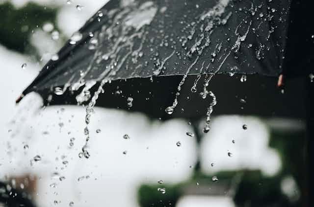 Rain water dribbles off the edge of an umbrella.