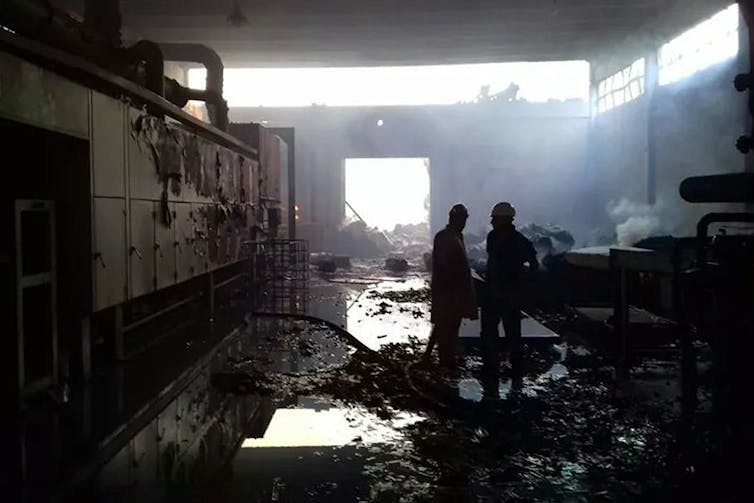 Two firefighters stand in puddles in a burned-out between .