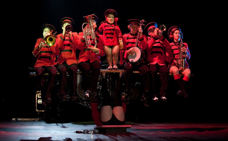 A strong woman holds up a brass band on her legs